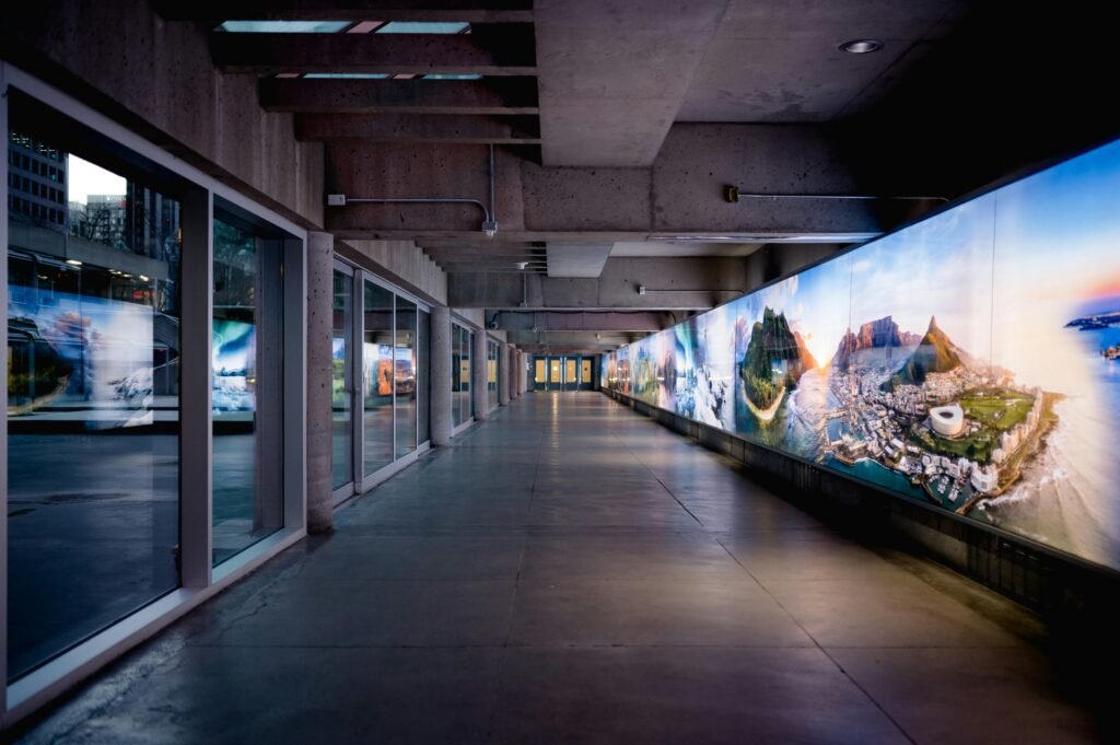 LCD vs dvLED: por que o LED direto se tornou o padrão em projetos modernos 1 A modern corridor lined with vibrant scenic displays under concrete architecture.